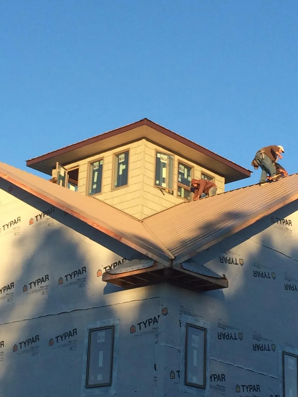 Roofers working around a rooftop cupola on a new metal roof at sunset — Roof Waterproofing in Black Creek by Roofing Brothers